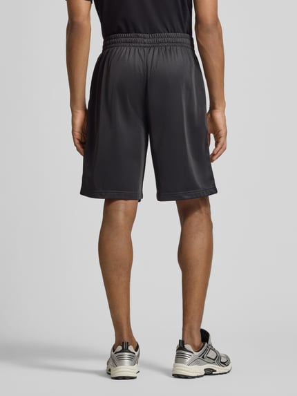 Männermodel trägt Shorts mit Logo und Eingrifftaschen von EA7 Emporio Armani, Relaxed-Fit, elastischer Bund, Ganzkörperansicht Rückansicht