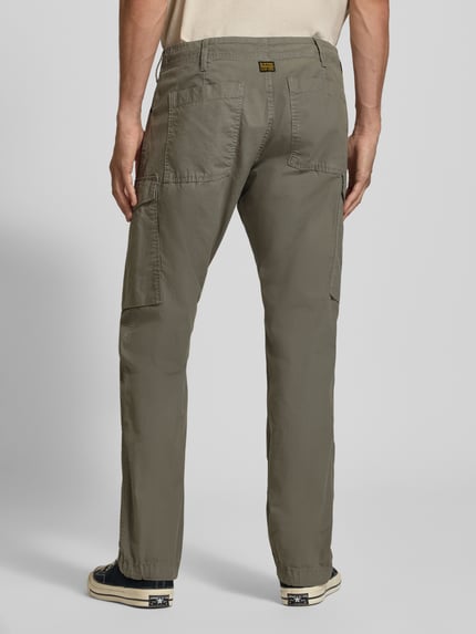 Männermodel trägt Regular Fit Cargohose aus reiner Baumwolle von G-Star RAW in Olivgrün, lockerer Schnitt, strukturierte Oberfläche, Ganzkörperansicht Rückansicht.