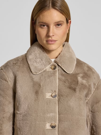 Vrouwenmodel draagt Regular Fit Webpelzjacke mit Umlegekragen model 'NEW CILO' van Selected Femme, look: effen, imitatiebont, knoopsluiting, lange mouw, platte kraag, steekzakken, rompzoom paspelnaad, materiaalverwerking: imitatiebont. Nahaufnahme bovenlichaam.