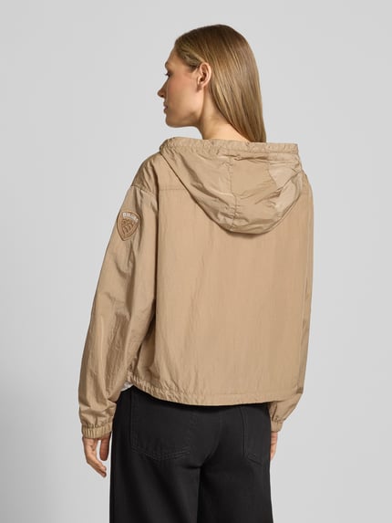 Frauenmodel trägt Trekking Jacke mit Kapuze Modell 'BURRAGE' von Blauer Usa in Beige, gerader Schnitt, Rückenansicht, Detailaufnahmen.