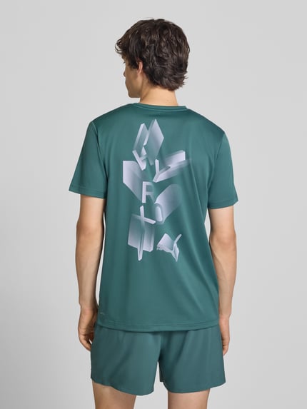 Männermodel trägt groen Regular Fit Sport-T-Shirt mit Logo-Print Modell 'M PUMA X HYROX' van PUMA Performance, Ganzkörperansicht Rückansicht.