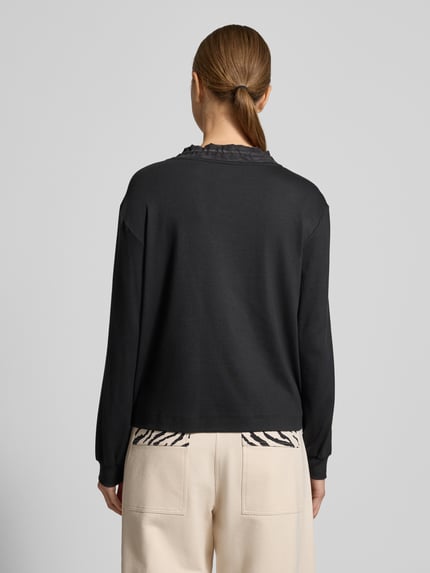 Frauenmodel trägt Longsleeve mit Rundhalsausschnitt von Marc Cain in Schwarz, lockerer Schnitt, gerippte Ärmel, Rückenansicht, Ganzkörperansicht Rückansicht. Baumwoll-Elasthan-Mix, Tunnelzug, Rückenlänge 53 cm bei Größe 36.