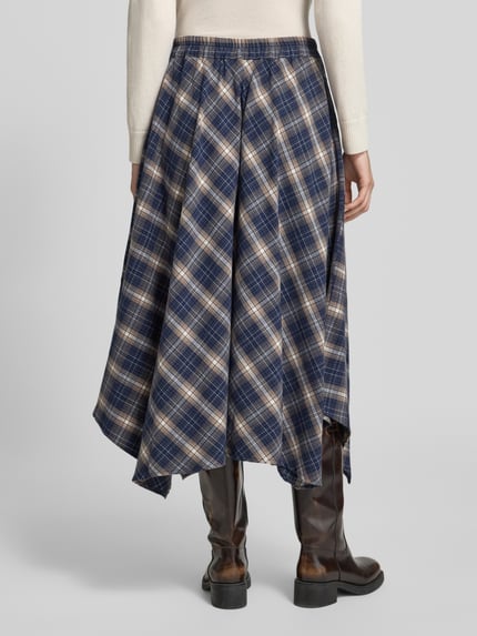 Frauenmodel trägt Midi-Rock mit asymmetrischem Saum Modell 'VMTILDA' von VERO MODA, kariertes Allover-Muster, Webware, Ganzkörperansicht Rückansicht.