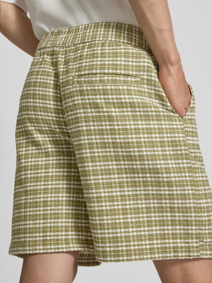 Männermodel trägt Shorts mit Strukturmuster Modell 'Kander' von Carhartt Work In Progress, grün-weiß kariert, Nahaufnahme Rückansicht