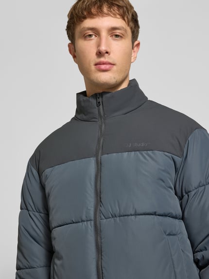 Männermodel trägt Steppjacke mit Stehkragen Modell 'RAZE' von JACK & JONES in Dunkelgrau, Regular Fit, Nahaufnahme Oberkörper.