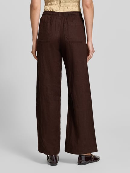 Frauenmodel trägt Leinenhose mit elastischem Bund Modell 'Mileni resort' von OPUS in Dunkelbraun, Wide-Leg-Fit, Ganzkörperansicht Rückansicht, französische Eingrifftaschen, Gesäßtaschen, reines Leinen, Bundweite 38 cm, Innenbeinlänge 80 cm bei Größe 36.
