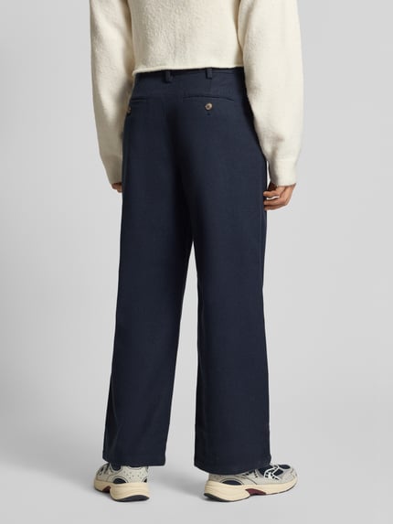 Mannelijk model draagt Hose mit gelegten Falten und Gesäßtaschen van PROHIBITED in donkerblauw, materiaalmix met viscose, relaxed fit, knoop- en ritssluiting, plooien, achterzakken; binnenbeenlengte 75 cm bij maat 32, bandwijdte 40 cm; Ganzkörperansicht Rückansicht.