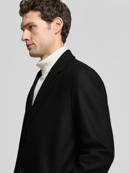 Männermodel trägt langen Wollmantel mit Labelopschrift Modell 'Malte2641' van HUGO, kleur: effen, regular fit, detailopname bovenlichaam.
