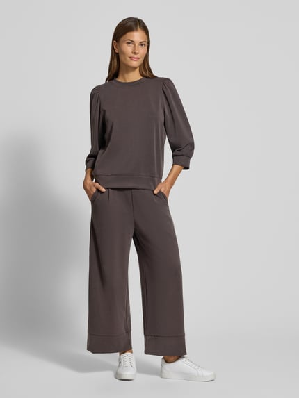 Frauenmodel trägt Sweatshirt mit Puffärmeln und Rundhalsausschnitt von Rich & Royal, braun, Stoff mit glatter Textur, Ganzkörperansicht von vorne. Micromodal-Mix mit Stretch-Anteil, Regular Fit, Damenmode.