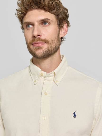 Männermodel trägt Custom Fit Freizeithemd aus reiner Baumwolle von Polo Ralph Lauren in cremefarben, glatte Textur, Nahaufnahme Oberkörper.