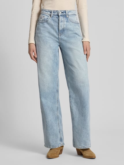 Frauenmodel trägt Wide Leg Jeans aus Baumwoll-Mix von Tommy Jeans in hellem Denim mit Label Patch und 5-Pocket-Design, Ganzkörperansicht von vorne.