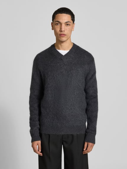 Männermodel trägt Regular Fit Pullover mit V-Ausschnitt von ANNARR in Dunkelgrau, Strick-Optik, gerippte Abschlüsse, Ganzkörperansicht von vorne.