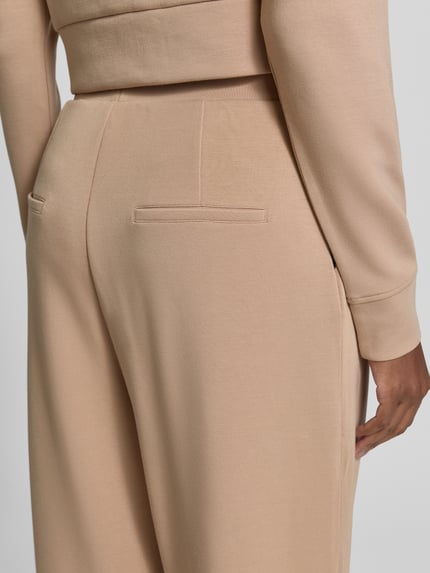 Frauenmodel trägt Barrel Fit Sweatpants mit elastischem Bund von Christian Berg Woman, beigefarbener Material-Mix mit Modal-Anteil, Detailaufnahme.