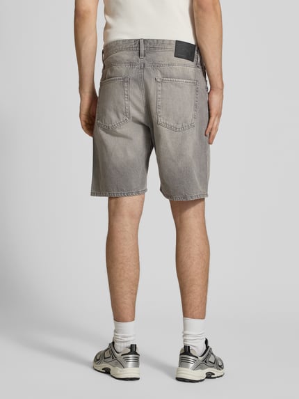 Männermodel trägt Loose Fit Jeansshorts mit Eingrifftaschen Modell 'TONY' von Jack & Jones in grauem Used-Look, Reine Baumwolle, Ganzkörperansicht Rückansicht.