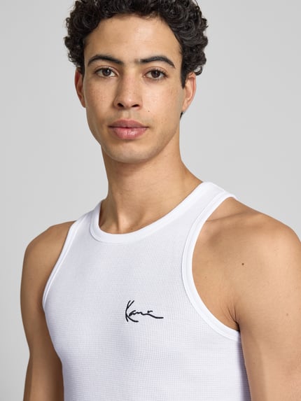 Männermodel trägt Slim Fit Top mit Logo-Stitching von KARL KANI in Weiß aus Baumwoll-Mix, Rundhalsausschnitt, Nahaufnahme Oberkörper. Rückenlänge bei Größe M: 68 cm.