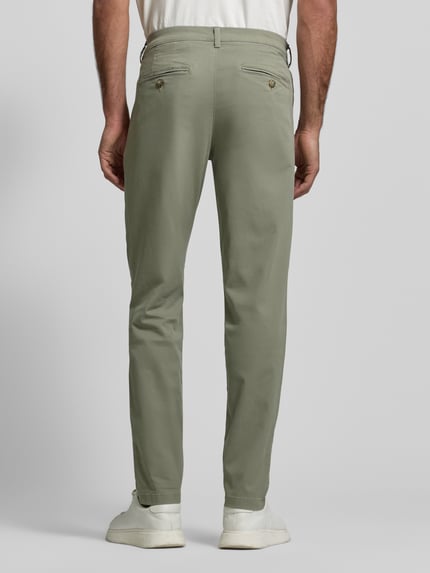 Mężczyznamodel nosi Slim Fit Chino aus Bio-Baumwoll-Mix Modell '175-SLIM NEW MILES' von Selected Homme, efekt: jednolity kolor, krój slim fit, średni stan, wpuszczane kieszenie, kieszenie z tyłu, mieszanka bawełny ekologicznej, widok całopostaciowy z tyłu.