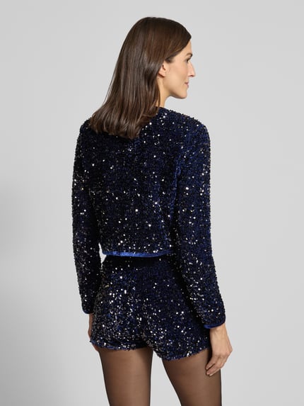 Frauenmodel trägt Bolero mit Pailletten und Schnürung Modell 'XTURNER' von Mango, cropped, dunkelblau, Ganzkörperansicht Rückansicht.