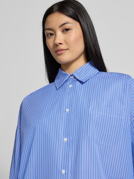 Vrouwenmodel draagt blauwe blouse met lange mouwen van katoen met fijne strepen, Loose Fit Langarmbluse aus reiner Baumwolle Modell 'OVATTA' van Weekend Max Mara, Dames Langarmbluse, close-up bovenlichaam.