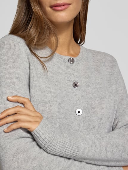 Frauenmodel trägt Cardigan aus Wolle mit Rundhalsausschnitt von Christian Berg Woman, hellgrau, feine Struktur, Nahaufnahme Oberkörper.