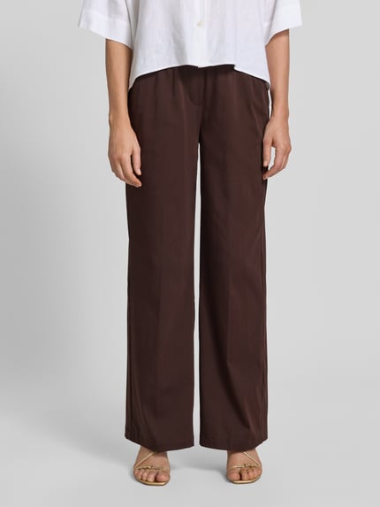 Kobiece model prezentuje spodnie materiałowe z mieszanki bawełny z dodatkiem streczu OPUS PANTS, krój loose fit, model 'Mucia Base', ciemnobrązowy, wpuszczane kieszenie z przodu, kieszenie z wypustką z tyłu, elastyczny pas, szerokość w rozmiarze 36: 31 cm, długość wewnętrzna nogawki w rozmiarze 36: 80 cm, zdjęcie: całkowity widok z przodu.