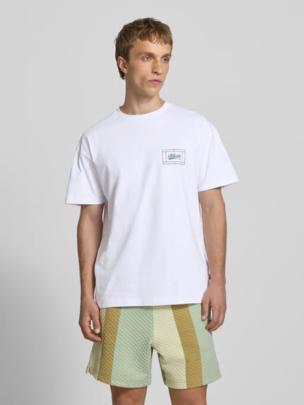Männermodel trägt Regular Fit T-Shirt mit Logo-Print von BLKVIS aus Reine Baumwolle, weiß, Rundhalsausschnitt, Ganzkörperansicht von vorne. Rückenlänge bei Größe M: 67 cm.