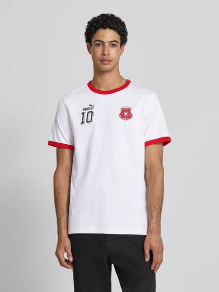 Männermodel trägt Herren T-Shirt aus Baumwolle Modell 'FUTURE' von PUMA PERFORMANCE in Weiß mit roten Label-Details, Gerader-Schnitt, Rundhalsausschnitt, Ganzkörperansicht von vorne. Rückenlänge bei Größe M 70 cm.