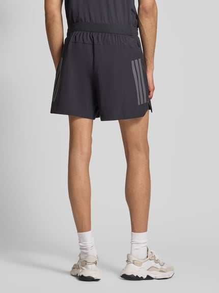 Männermodel trägt Regular Fit Sport-Shorts mit Logo-Print von adidas Training, Optik: Unifarben, Bundabschluss: elastisch, Ganzkörperansicht Rückansicht.