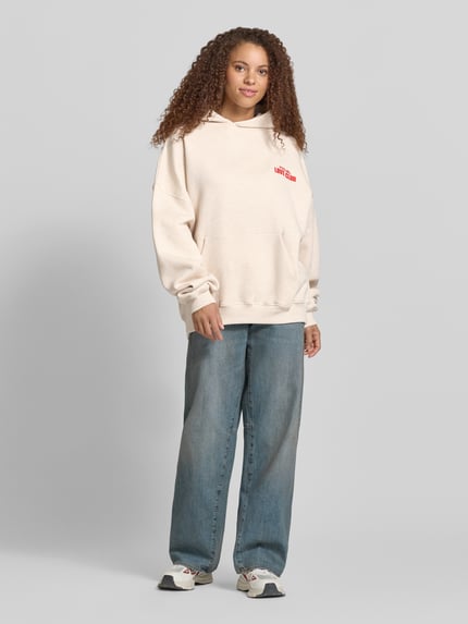 Vrouwenmodel draagt hoodie met statementprint model 'Love Club' van Karo Kauer, puur katoen, oversized fit, kangoeroezak, capuchon, voorkant volledig zichtbaar.