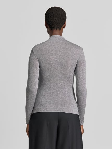 Frauenmodel trägt Longsleeve in Wickel-Optik von windsor., melierte Optik in Grau, taillierter Schnitt, Ganzkörperansicht Rückansicht. Elastischer Lyocell-Woll-Mix, Rückenlänge 58 cm bei Größe 36, Label-Applikation sichtbar.