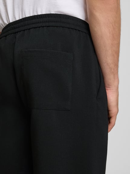 Männermodel trägt Loose Fit Shorts mit elastischem Bund Modell 'WILL' van Only & Sons, unikleuren, elastische taille met trekkoord, steekzakken, achterzak, detailopname achterkant.