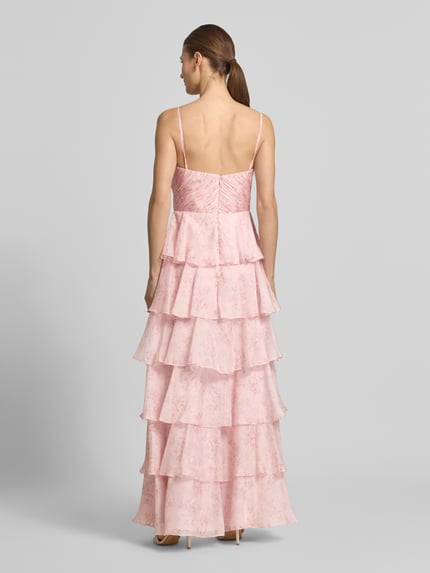 Frauenmodel trägt Abendkleid mit Volantsaum und Spaghettiträgern von Hey Kyla aus rosafarbenem Chiffon, A-Linie, Maxikleid, V-Ausschnitt, rückseitiger Reißverschluss, Rückenlänge 147 cm, Brustweite 33 cm, Ganzkörperansicht Rückansicht.