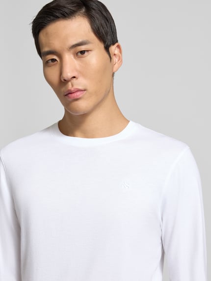 Männermodel trägt Longsleeve mit gerippten Abschlüssen von Scotch & Soda in Weiß, Reine Baumwolle, Regular-Fit, Rundhalsausschnitt, Nahaufnahme Oberkörper.