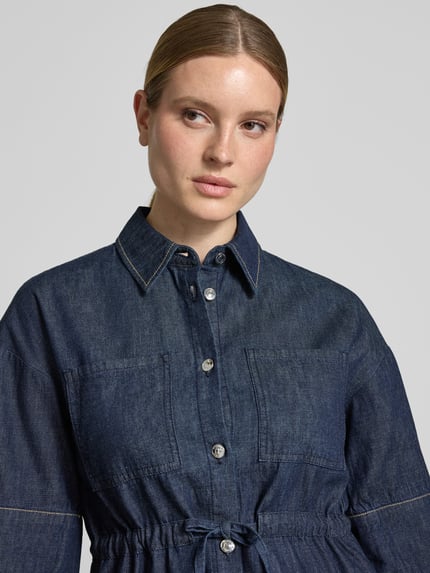 Frauenmodel trägt Hemdbluse in Denim-Optik mit Brusttaschen von Comma, reine Baumwolle, taillierte Passform, Halbarm, Nahaufnahme Oberkörper.