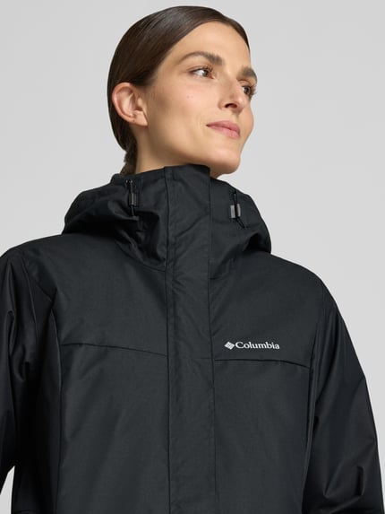 Frauenmodel trägt Regular Fit Jacke mit Logo-Print Modell 'Hikebound' von Columbia in Schwarz, glatte Textur, Nahaufnahme Oberkörper. Damen Jacke mit Tunnelzug, Rückenlänge 75 cm, Schulterbreite 42 cm, Brustweite 52 cm, Ärmellänge 66 cm.
