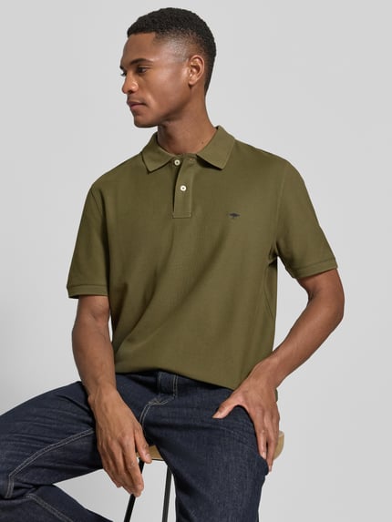 Männermodel trägt Regular Fit Poloshirt mit Logo-Stitching von Fynch-Hatton in olijfgroen, puur katoen, polokraag, korte mouw, ruglengte 70 cm bij maat M, Ganzkörperansicht von vorne.