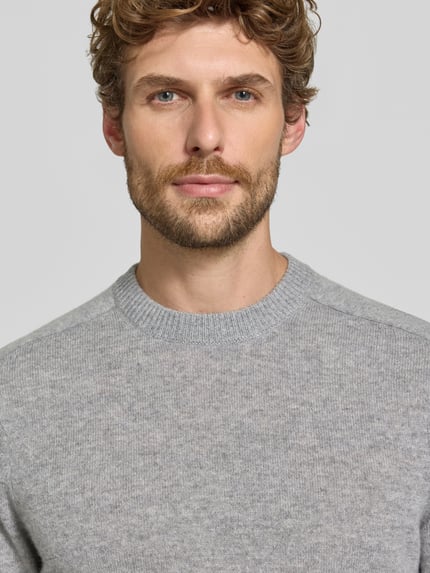 Männermodel trägt Regular Fit Strickpullover aus reinem Kaschmir von FTC Cashmere in hellgrau, weiche Textur, Nahaufnahme Oberkörper.