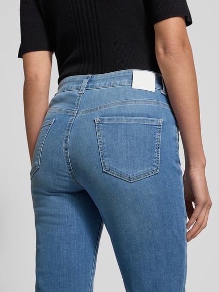 Frauenmodel trägt Slim Fit Jeans im 5-Pocket-Design von Marc Cain, blauer Baumwoll-Mix mit Stretch, Label-Detail, Ganzkörperansicht Rückansicht.
