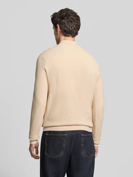 Männermodel trägt Slim Fit Strickpullover aus Baumwoll-Mix mit Troyer-Kragen von Profuomo, beiger Farbton, elastische Abschlüsse, Ganzkörperansicht Rückansicht.