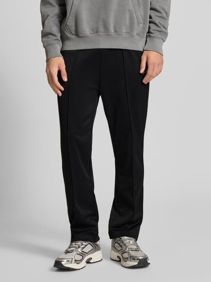 Männermodel draagt Jogpants met elastische band en labelstitching van Pegador, materiaalmix met katoen, regular fit, kleur zwart, binnenbeenlengte maat M 70 cm, Nahaufnahme onderlichaam, vooraanzicht.
