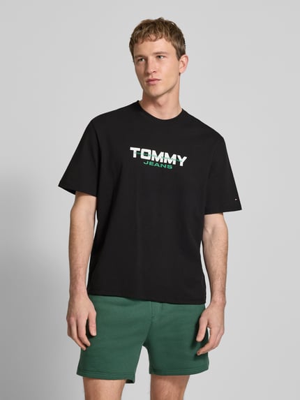 Männermodel trägt Regular Fit T-Shirt aus reiner Baumwolle von Tommy Jeans, Optik: Unifarben, Label-Schriftzug, Ganzkörperansicht von vorne.
