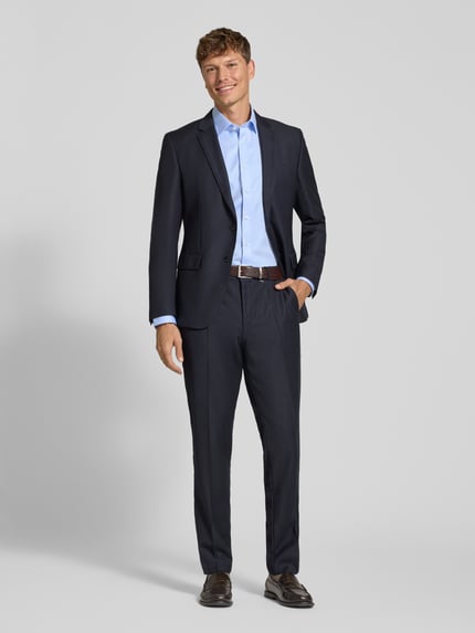 Männermodel trägt Regular Fit Businesshemd aus reiner Baumwolle von OLYMP, hellblau, kombiniert mit dunkelblauem Anzug, Ganzkörperansicht von vorne.