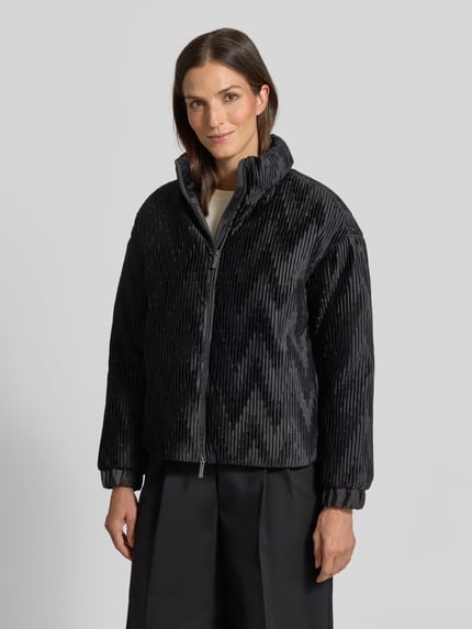 Frauenmodel trägt Jacke mit Zweiwege-Reißverschluss von Emporio Armani in Schwarz, Ripp-Optik, hoher Stehkragen, elastische Ärmelabschlüsse, gerade Passform, Ganzkörperansicht von vorne.