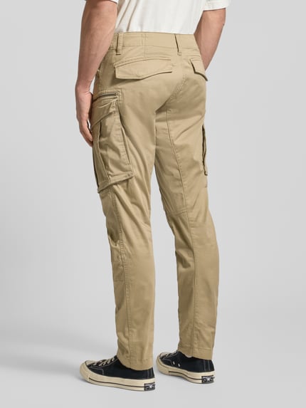 Männermodel draagt Regular Tapered Fit Cargobroek met ritszak van G-star, mix van katoen en elastaan, 5-pocketmodel, riemlussen, model Rovic, kleur beige, binnenbeenlengte 77 cm, bandwijdte 42 cm, ganzkörperansicht rückansicht.