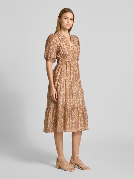 Frauenmodel trägt Midikleid aus Lyocell-Mix Modell 'Tanyssa' von Bash mit Allover-Paisley-Print, Tunika-Kragen, taillierte Passform, Halbarm, elastische Ärmelabschlüsse, dezente Beige- und Rosétöne, feine Musterstruktur, Ganzkörperansicht von vorne.