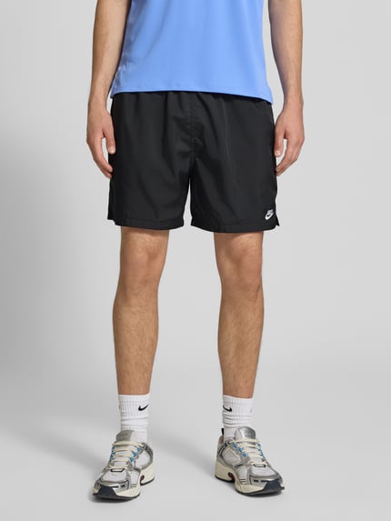 Männermodel trägt schwarze Shorts mit Label-Stitching und elastischem Bund von Nike, Regular-Fit, Tunnelzug, Ganzkörperansicht von vorne.