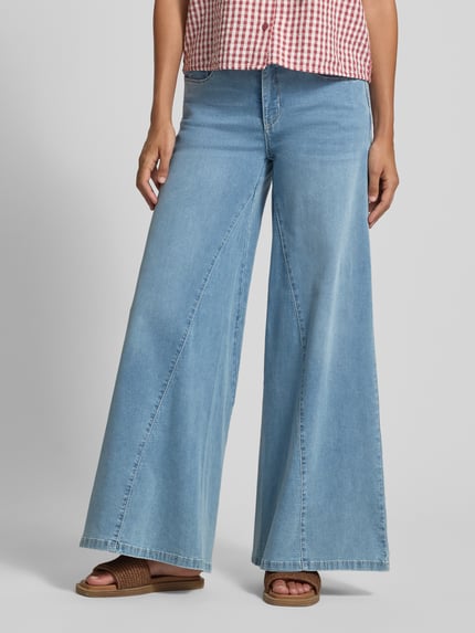 Vrouwenmodel draagt Wide Fit Jeans met sierstrik van MAC, lichtblauwe katoenmix, wide fit, 5-pocketmodel, knoop- en ritssluiting, bandwijdte 38 cm, binnenbeenlengte 82 cm, voorkant bovenlichaam tot voeten, nahaufnahme onderlichaam.