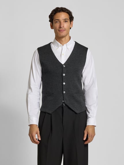 Männermodel trägt Slim Fit Weste aus Woll-Mix von Christian Berg Men in Dunkelgrau, Strick-Optik, Knopfleiste, V-Ausschnitt, Ganzkörperansicht von vorne.