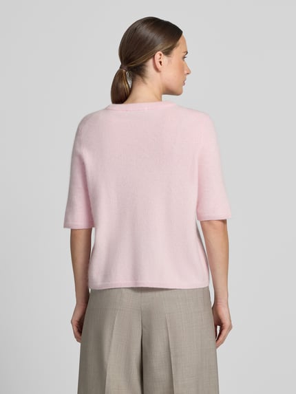 Frauenmodel trägt Regular Fit Strickpullover aus reiner Wolle von COMMA in zartem Rosa, feine Struktur, taillierte Passform, Ganzkörperansicht Rückansicht.