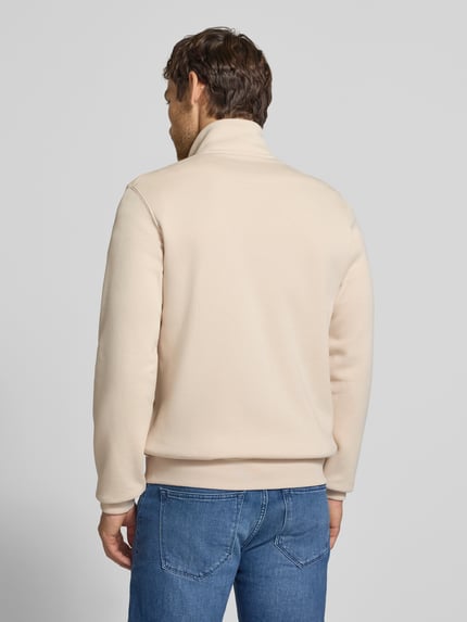 Männermodel trägt Regular Fit Sweatjacke aus Baumwoll-Mix von s.Oliver RED LABEL in Beige, glatte Textur, blaue Jeans, Ganzkörperansicht Rückansicht.