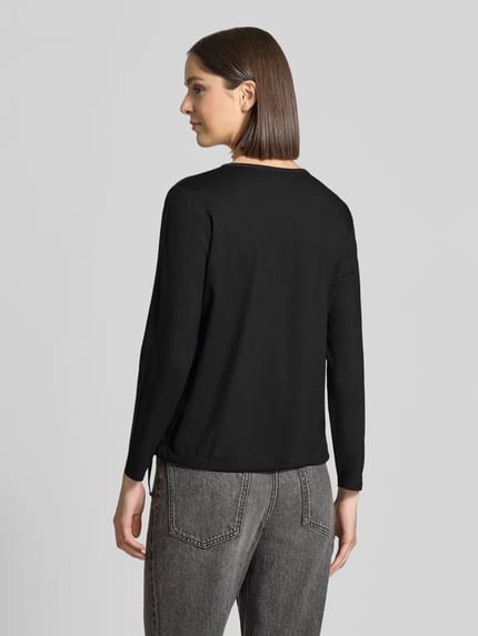 Vrouwenmodel draagt Regular Fit Bluse mit Brusttaschen van monari in effen zwart met Tuniekhals, Met siersteentjes, blouse met lange mouwen, ruglengte maat 36: 58 cm, mouwlengte maat 36: 58 cm, Ganzkörperansicht Rückansicht.